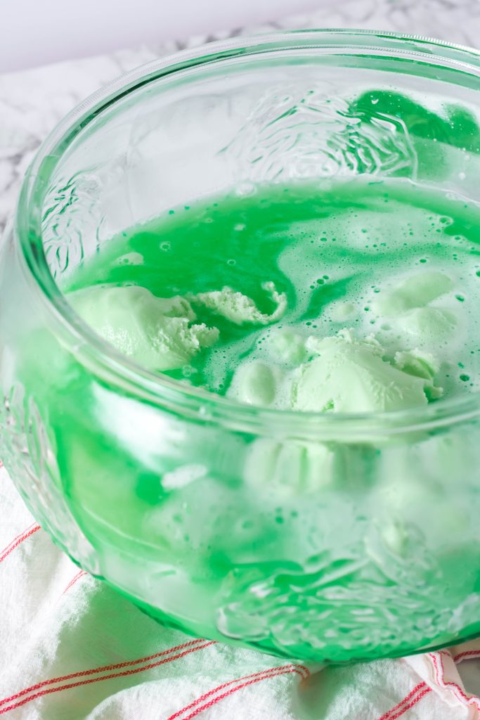 green grinch punch with large dollops of lime sherbet floating in a glass punch bowl