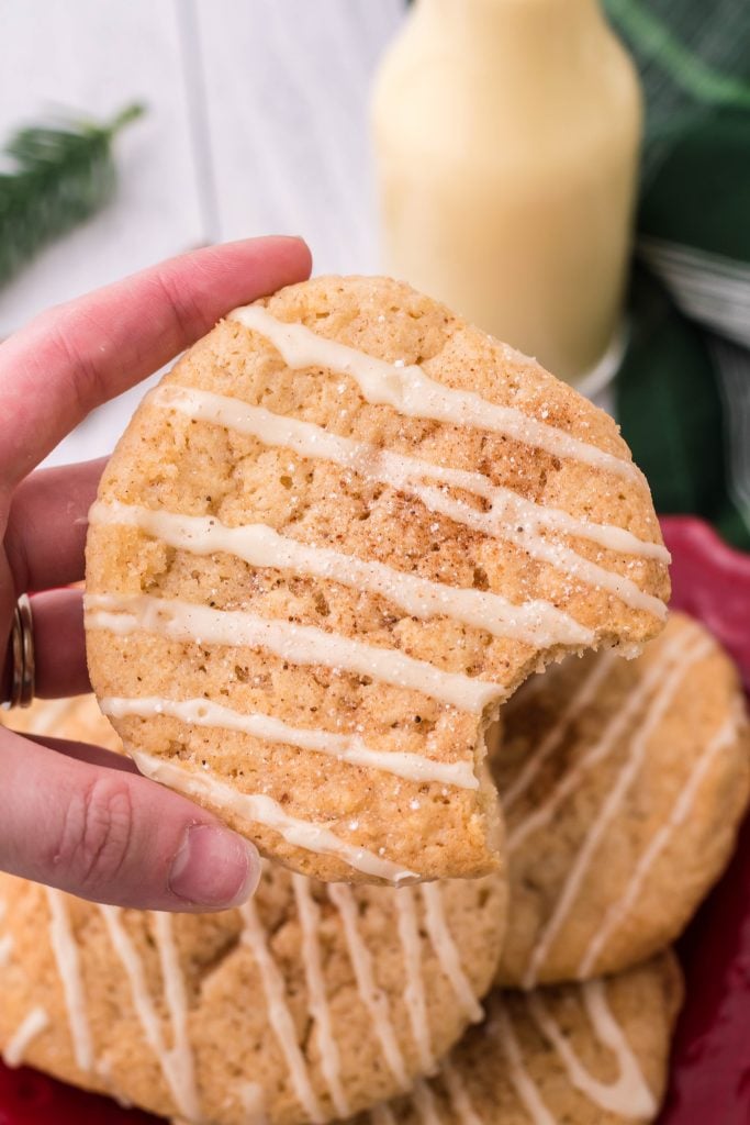iced eggnog cookie held up by a hand with a bite removed