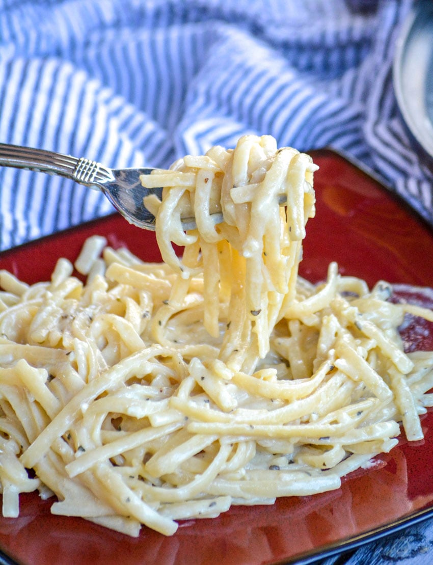 a fork lifting up a scoop of cheesy garlic parmesan pasta