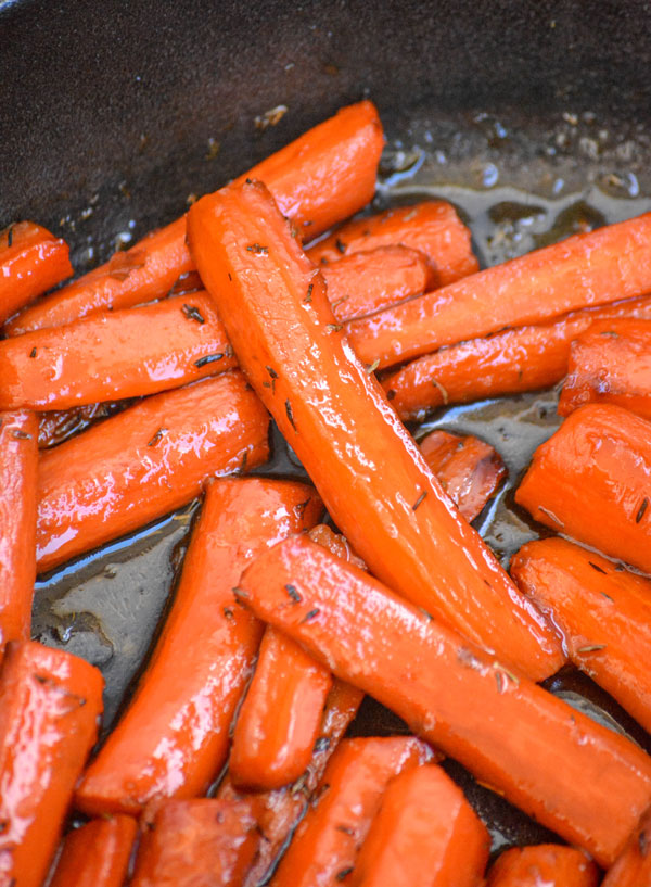 Maple Glazed Thyme Roasted Carrots shown in a cast iron skillet