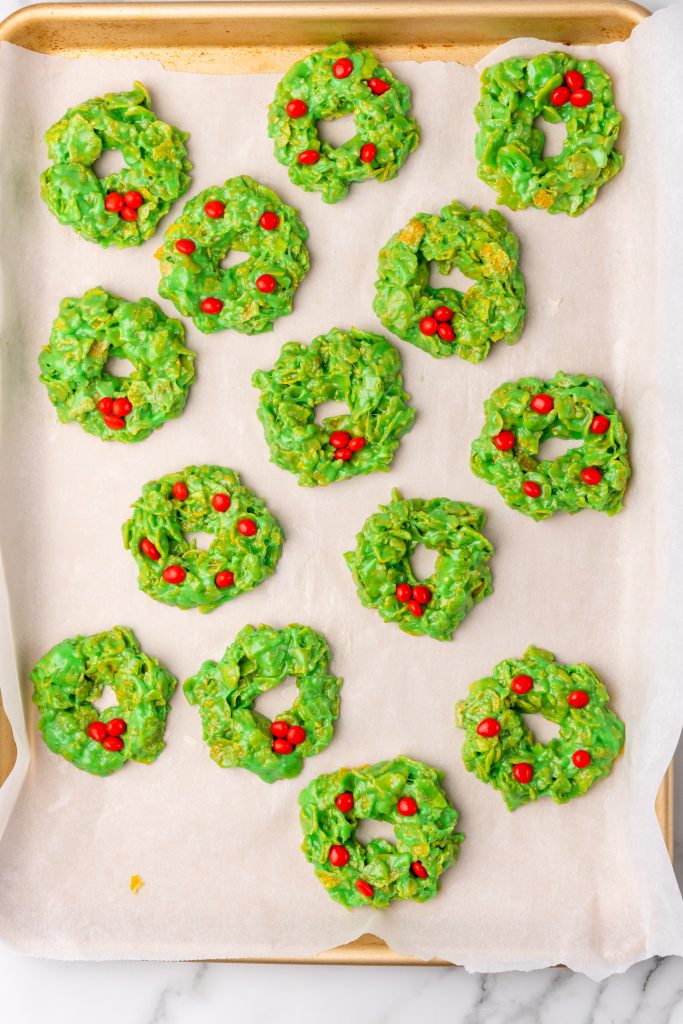 christmas wreath cookies arranged on a wax paper lined baking sheet