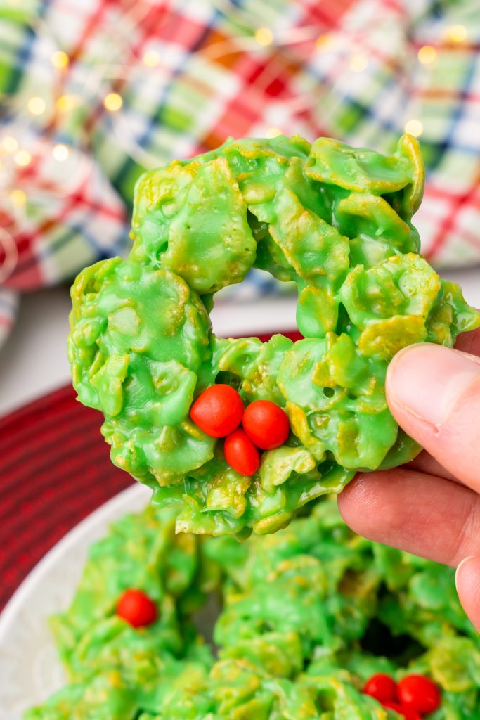 a hand holding up a decorated christmas wreath cookie