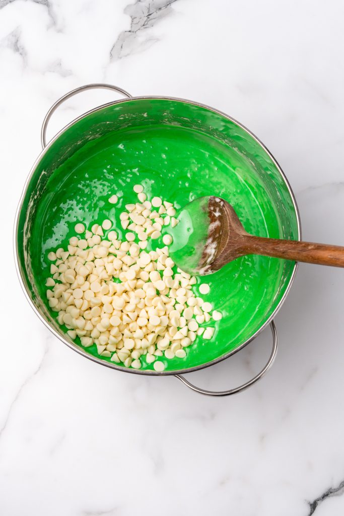 white chocolate chips in a pot of green melted marshmallows