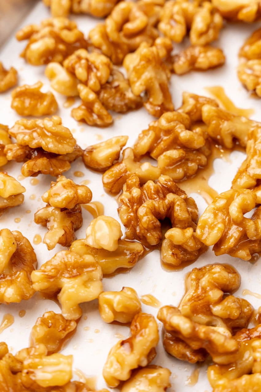 maple glazed walnuts spread out on a sheet of white parchment paper