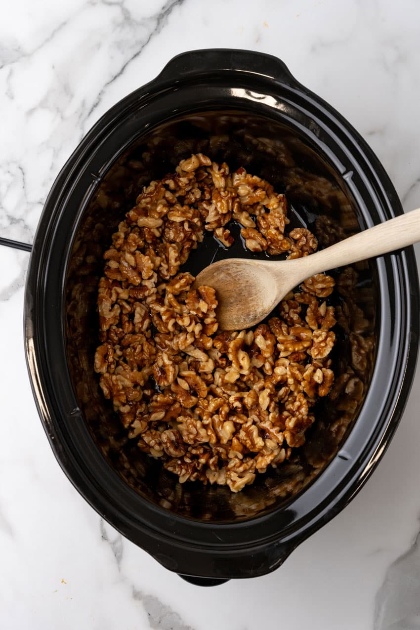 an overhead image showing walnuts, melted butter, and maple syrup in a black crock