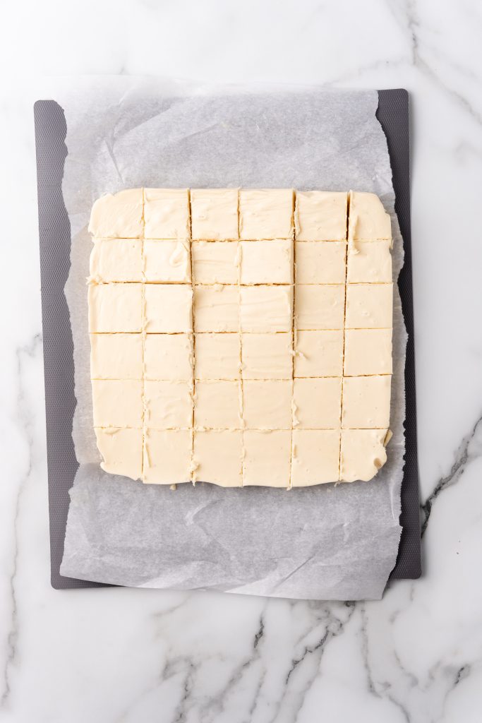 cut square pieces of 30 minute eggnog fudge on a parchment paper lined cutting board