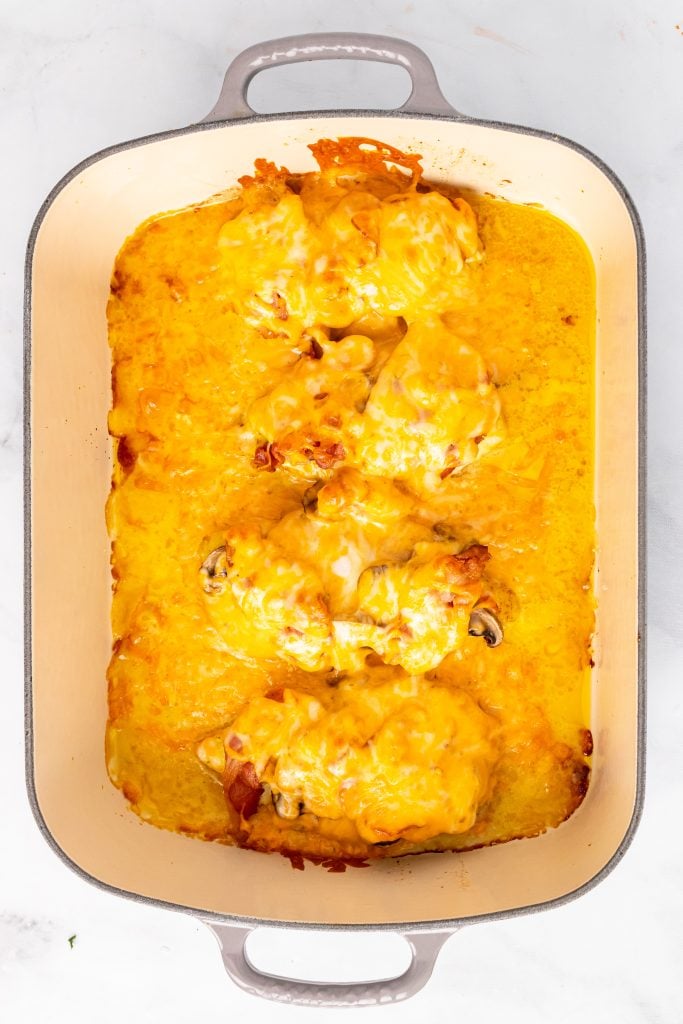chicken breasts in casserole dish smothered in melted cheddar cheese