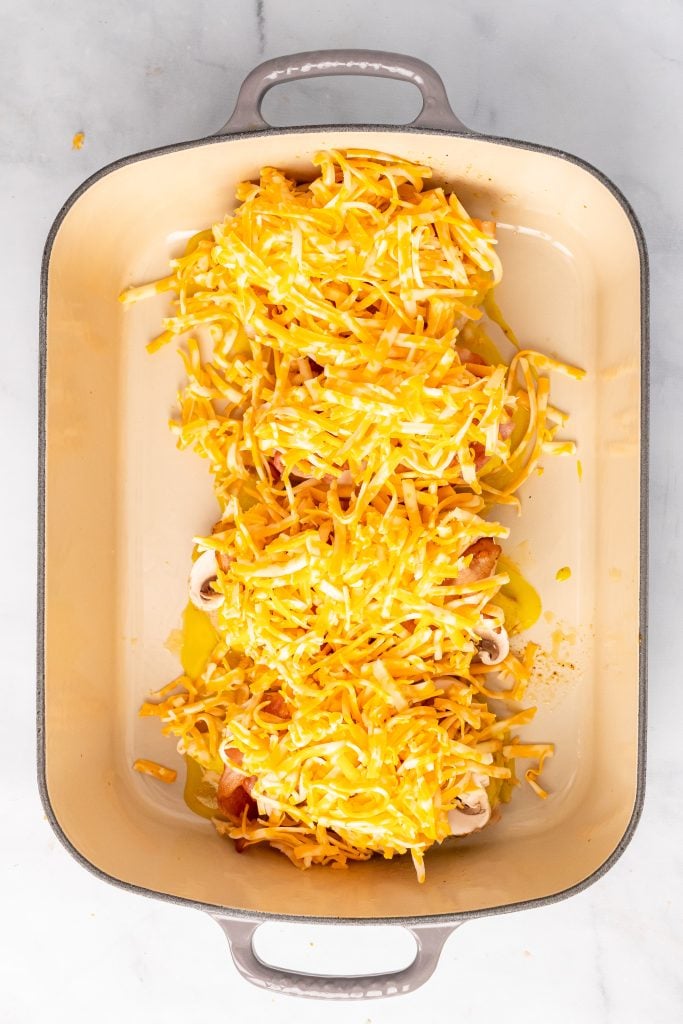 cheese covered cooked chicken breasts in a row in a shallow casserole dish