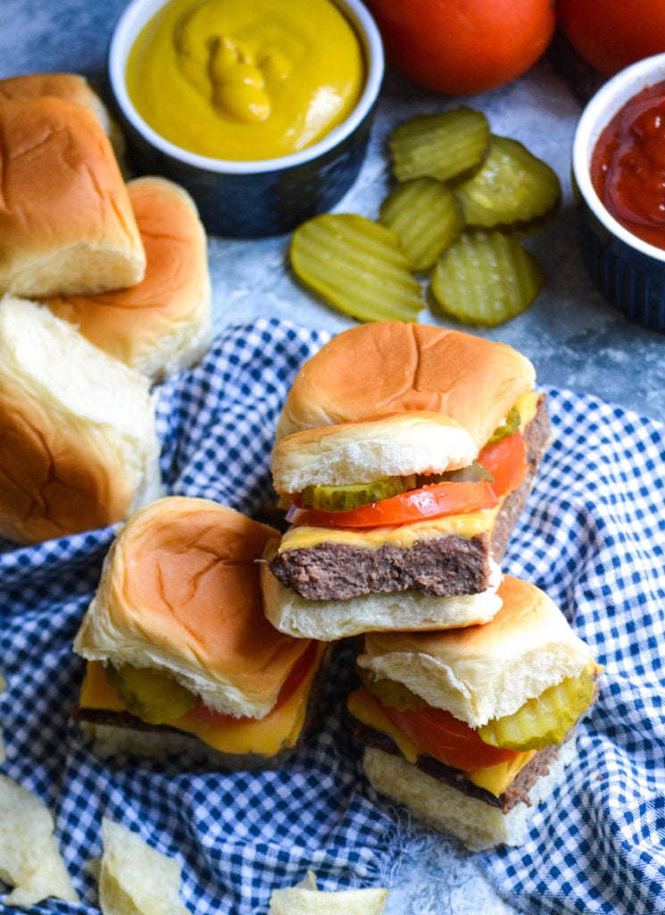 four cheeseburger sliders stacked on top of a blue checkered cloth napkin