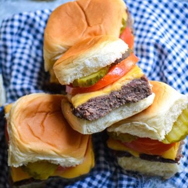 four cheeseburger sliders stacked on top of a blue checkered cloth napkin