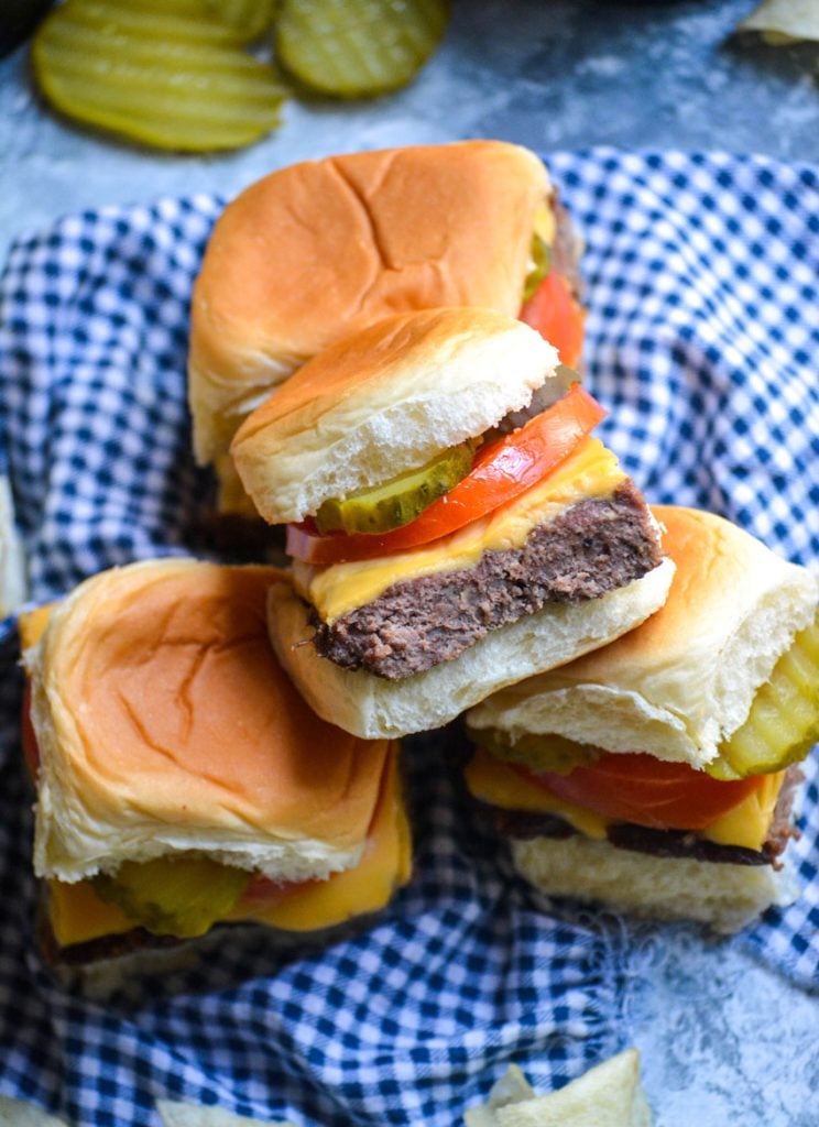 four cheeseburger sliders stacked on top of a blue checkered cloth napkin