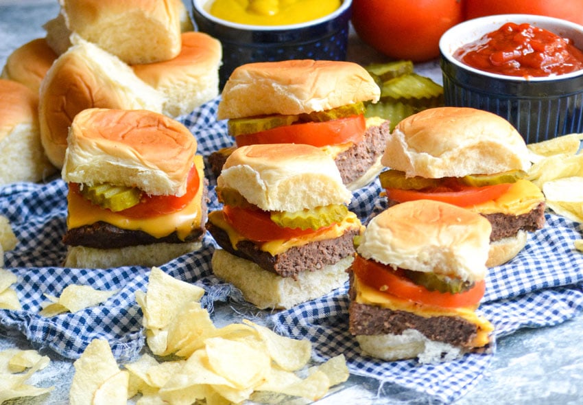 easy cheeseburger sliders next to chips on a blue checkered napkin