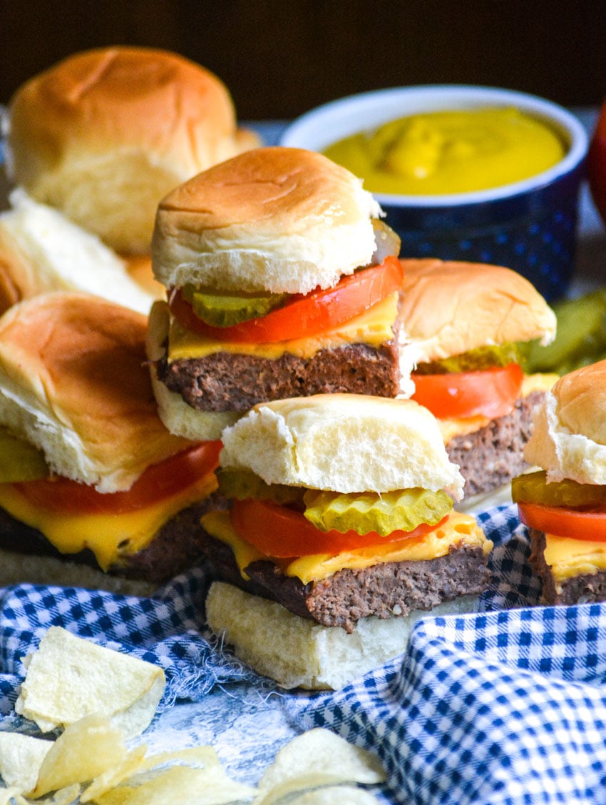 four cheeseburger sliders stacked on top of a blue checkered cloth napkin