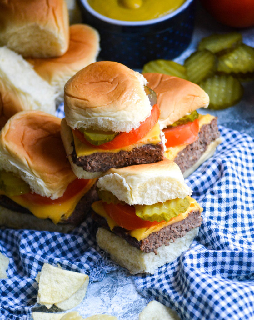 four cheeseburger sliders stacked on top of a blue checkered cloth napkin