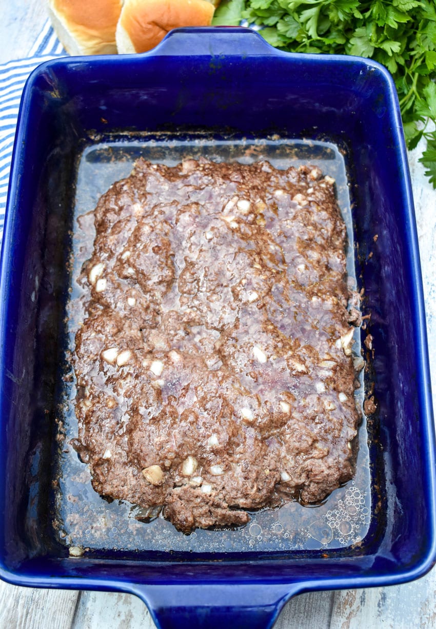 a large rectangular cooked hamburger patty in a blue casserole dish