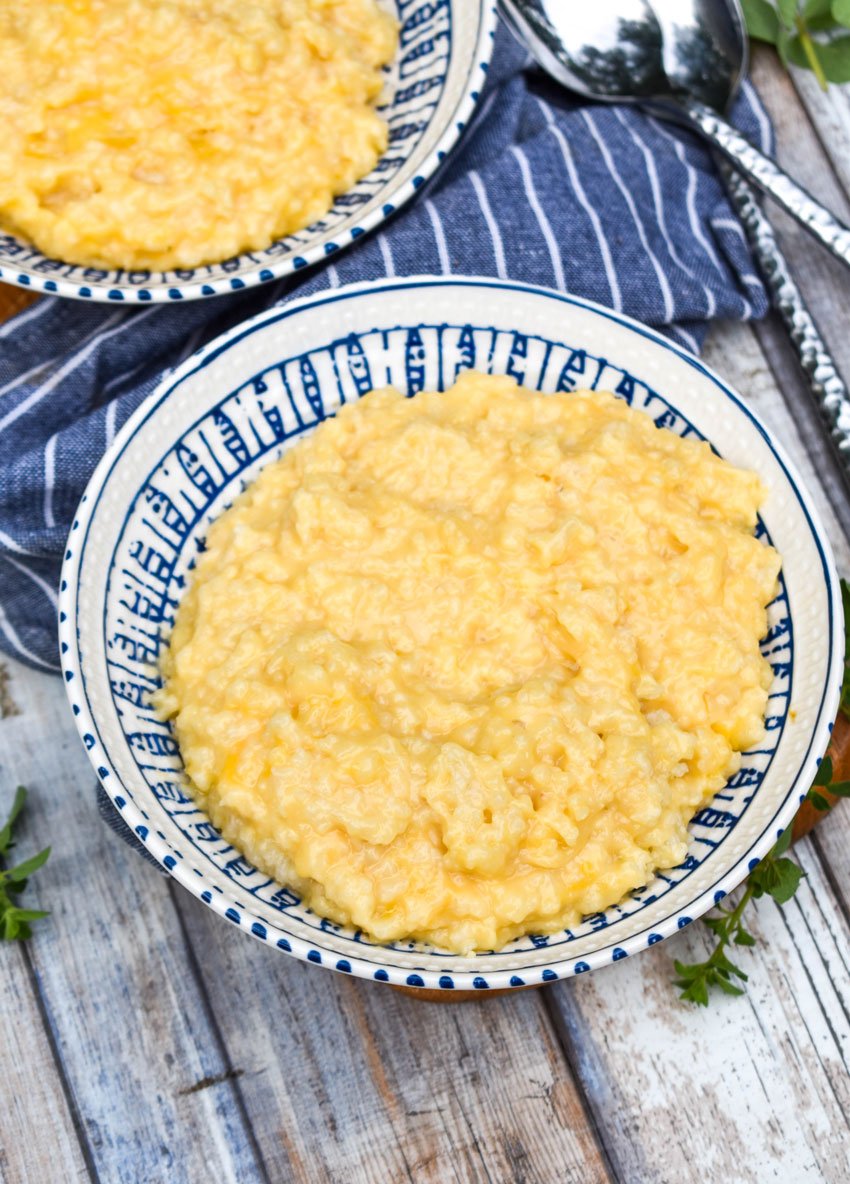 cheesy crock pot risotto in a blue & white bowl on a wooden cutting board