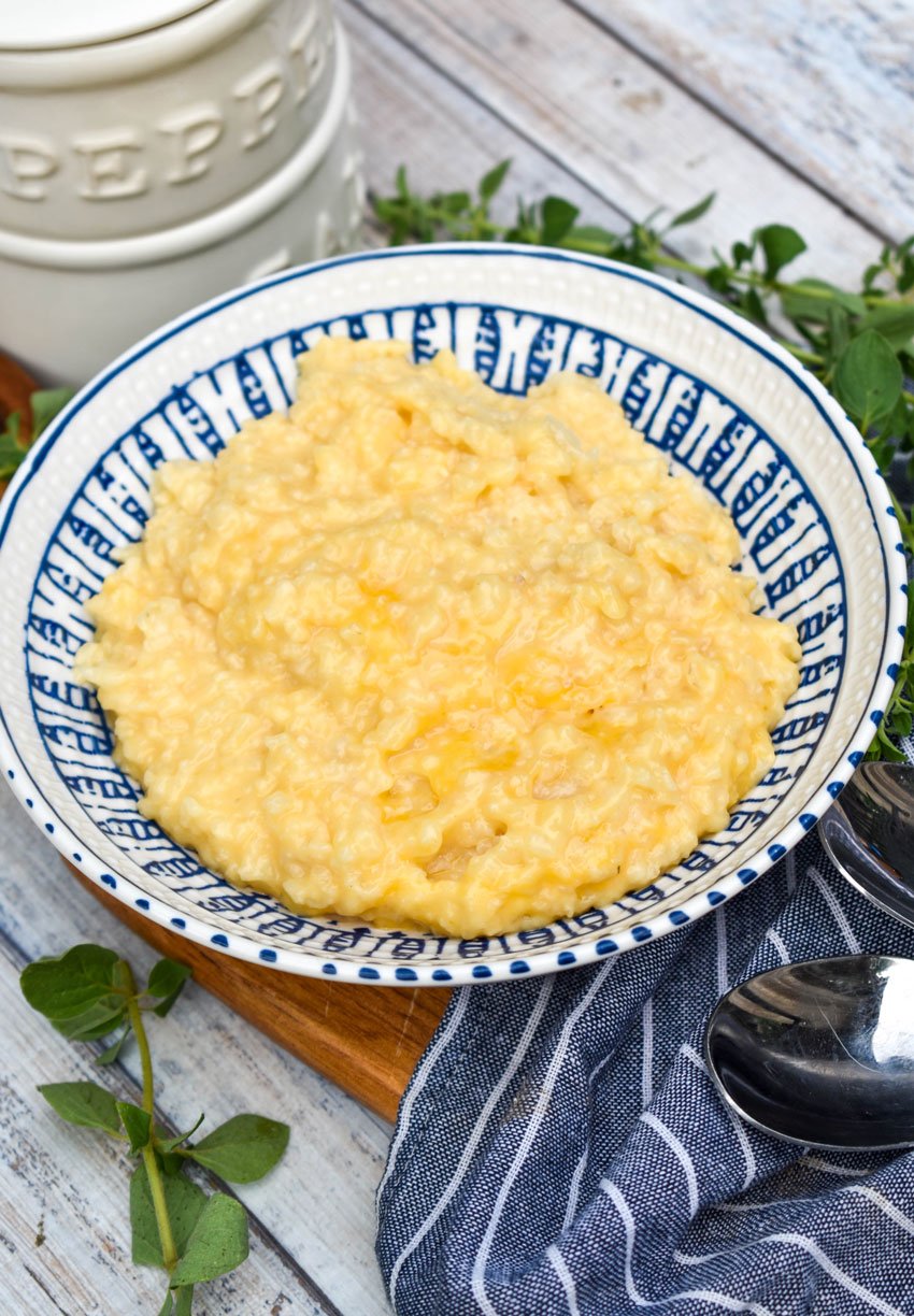 cheesy crock pot risotto in a blue & white bowl on a wooden cutting board