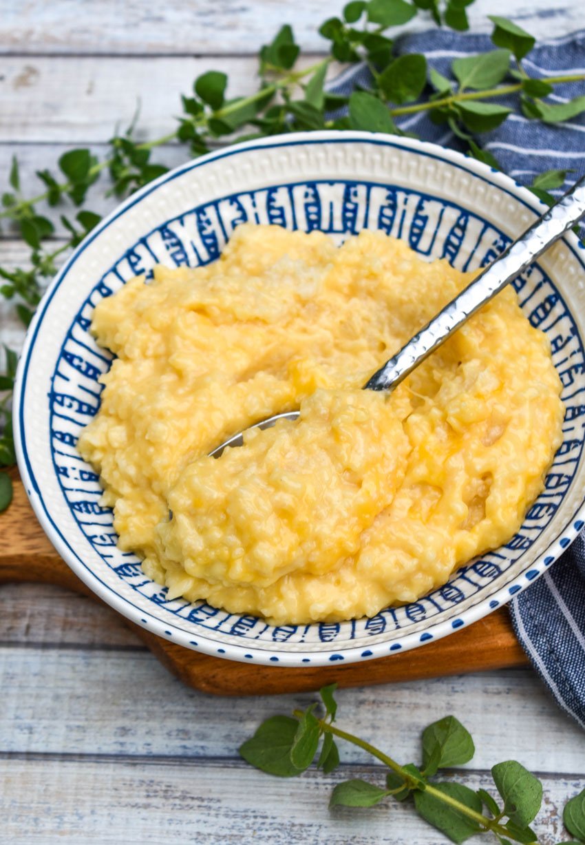 cheesy crock pot risotto in a blue and white bowl with a silver spoon