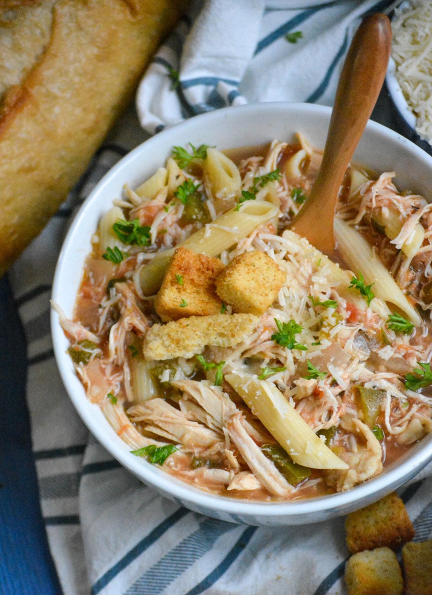 crockpot chicken parmesan soup served in bowls with extra parmesan cheese and a fresh baguette on the side