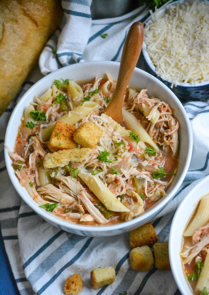 crockpot chicken parmesan soup served in bowls with extra parmesan cheese and a fresh baguette on the side