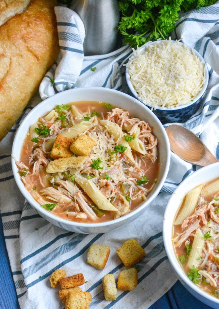 crockpot chicken parmesan soup served in bowls with extra parmesan cheese and a fresh baguette on the side