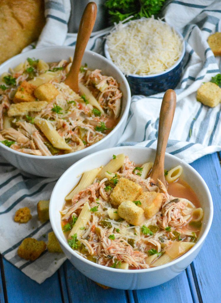 crockpot chicken parmesan soup served in bowls with extra parmesan cheese and a fresh baguette on the side