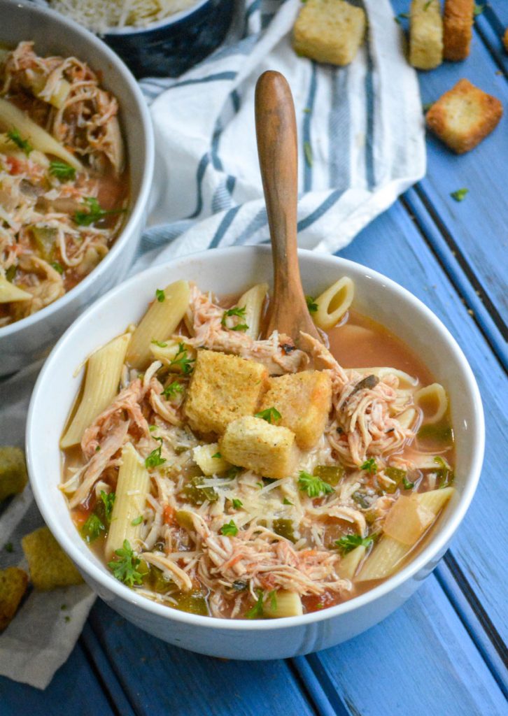 crockpot chicken parmesan soup served in bowls with extra parmesan cheese and a fresh baguette on the side