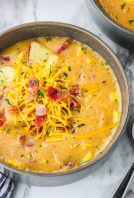corn and potato studded smoky bacon and cheddar chowder shown in gray soup bowls topped with shredded cheddar cheese and crisp bacon bits