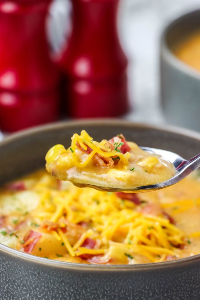 a silver spoon shown scooping up a spoonful of creamy, corn filled instant pot smoky bacon and cheddar chowder