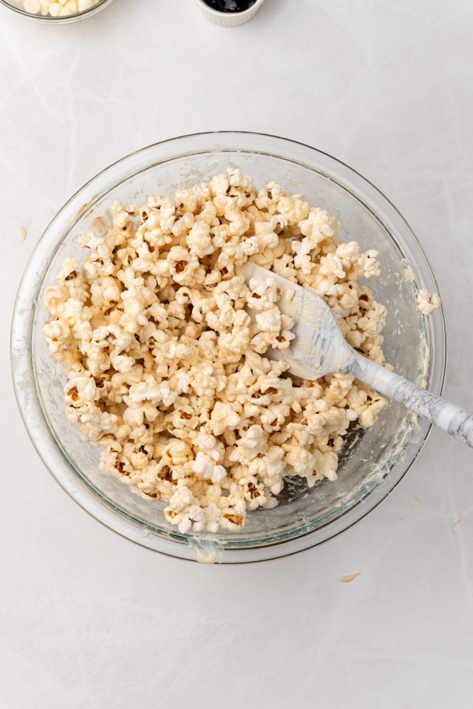 peanut butter white chocolate coated popcorn in a glass mixing bowl