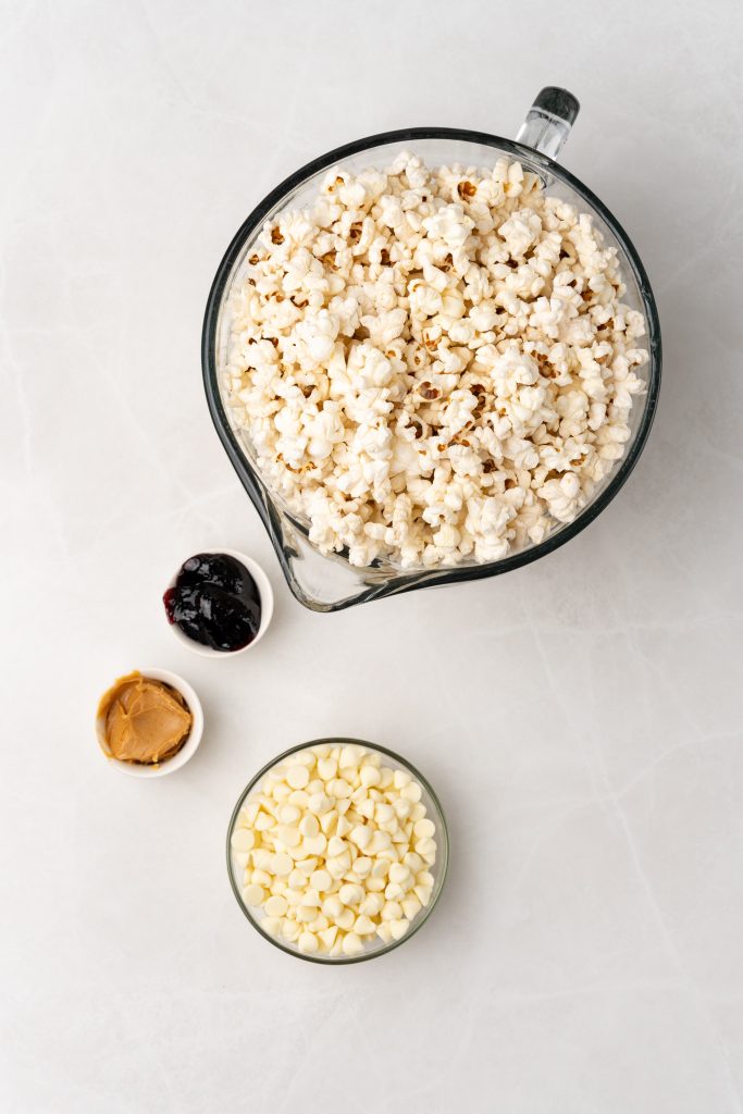 overhead image showing the measured ingredients needed to make a batch of peanut butter and jelly popcorn