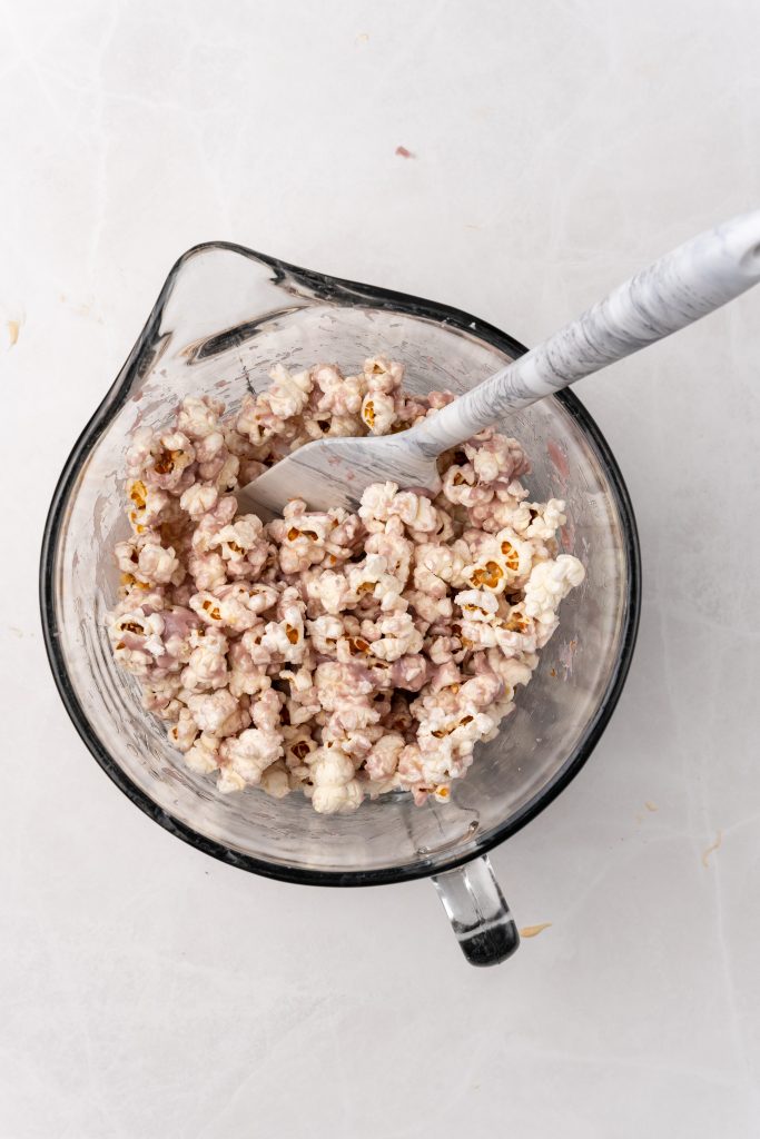 grape jelly flavored chocolate coated popcorn in a glass mixing bowl