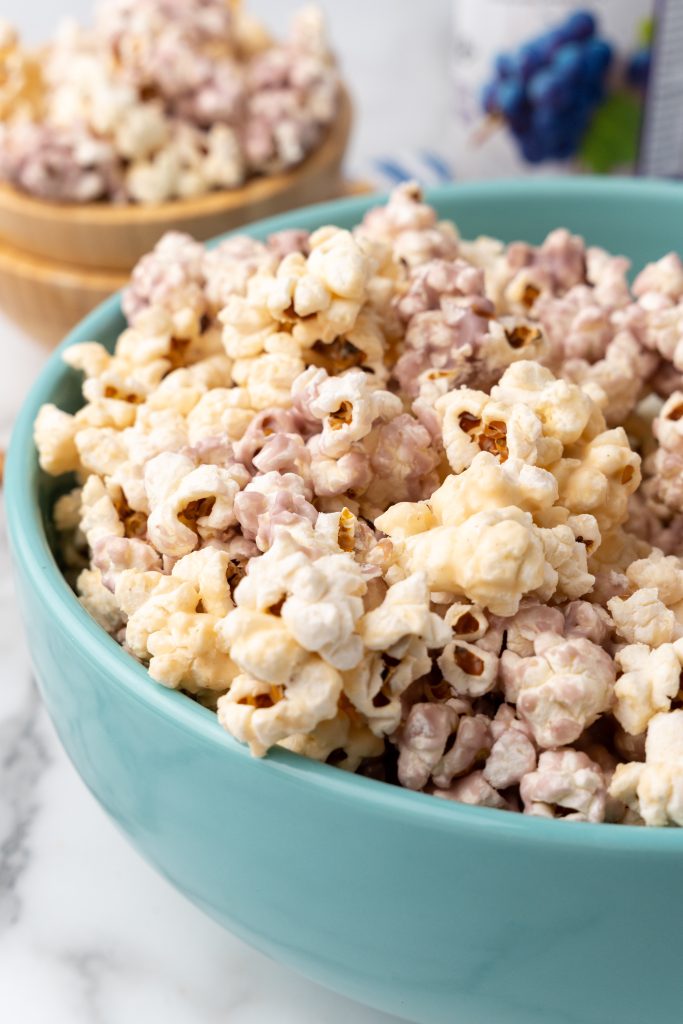 peanut butter and jelly popcorn in a large blue mixing bowl
