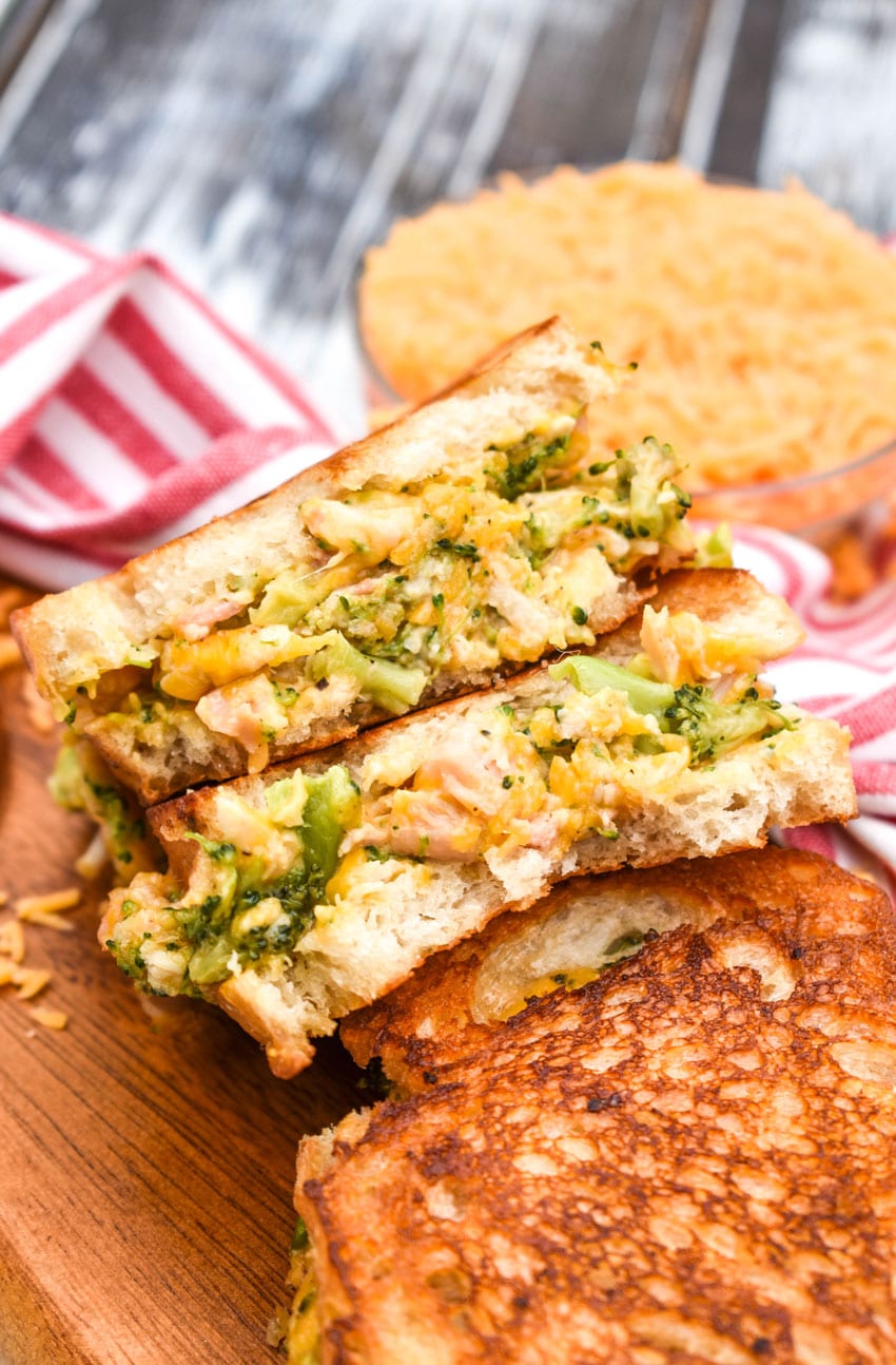 grilled cheese with chicken and broccoli cut in half and serve on a wooden serving platter