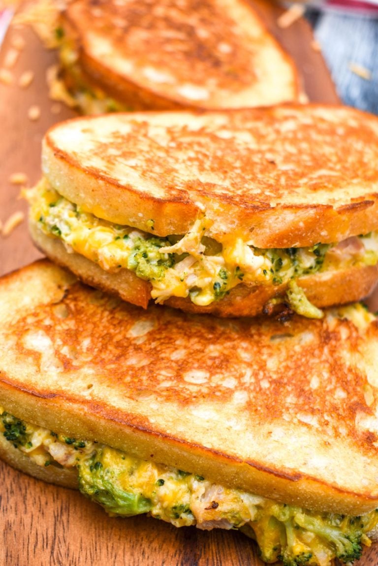 chicken and broccoli grilled cheese sandwiches stacked on a wooden cutting board