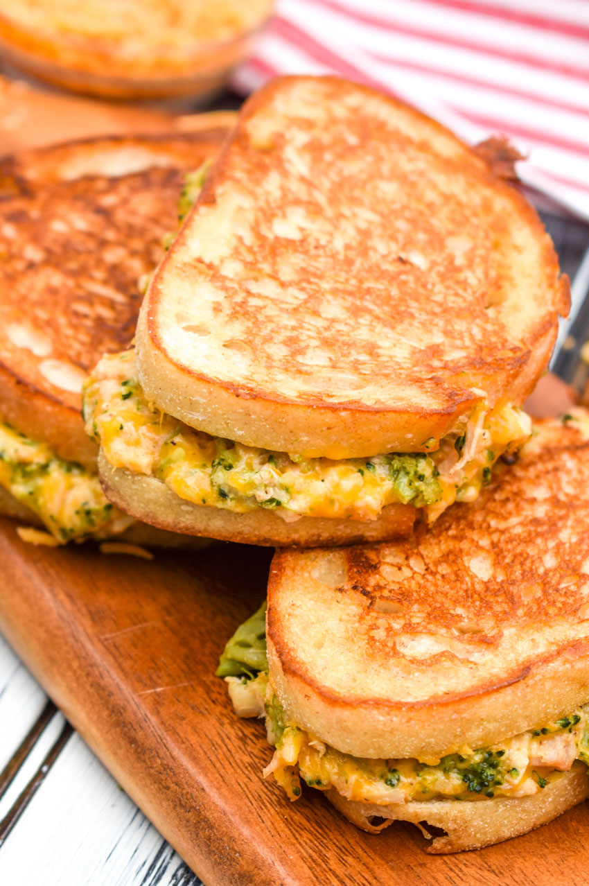 chicken and broccoli grilled cheese sandwiches stacked on a wooden cutting board