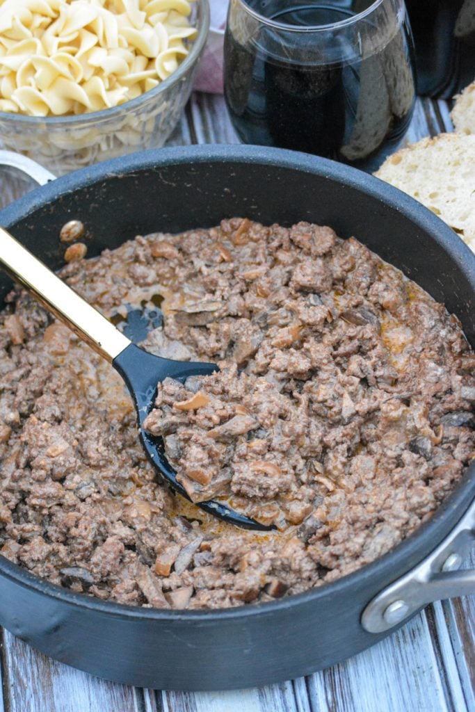 ground beef stroganoff in a black skillet with a serving spoon ready to ladle