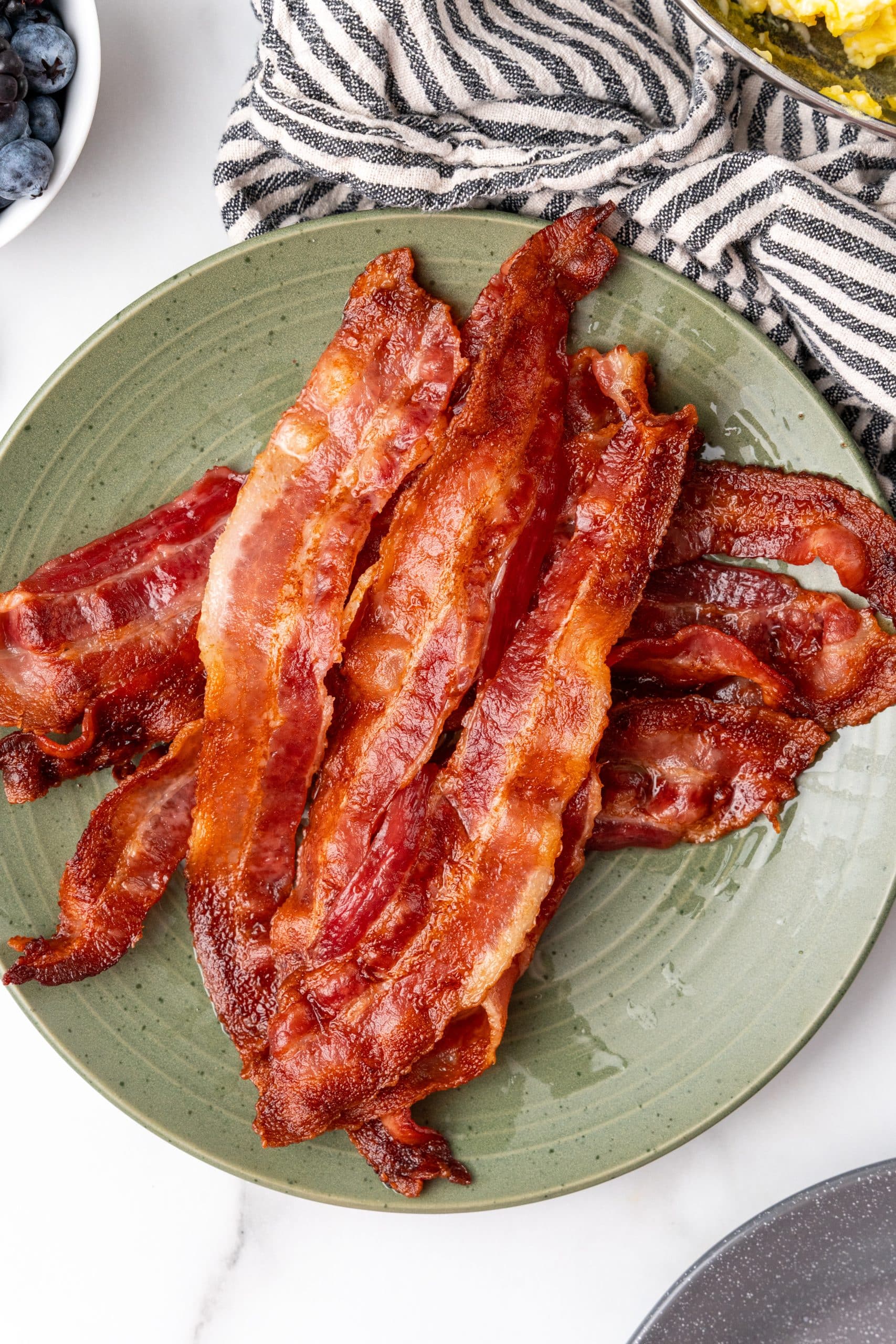 crispy slices of oven baked bacon stacked on a green plate