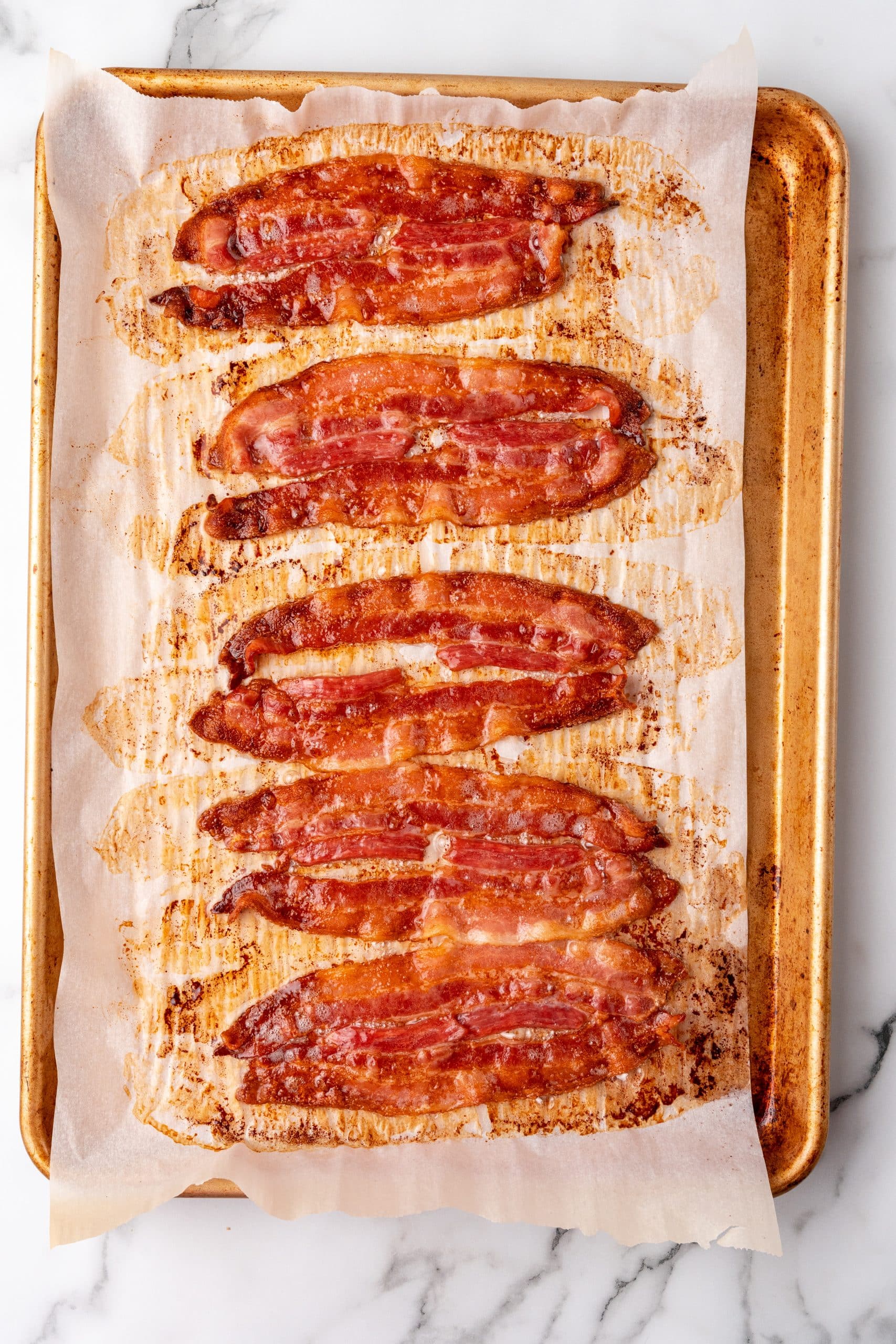slices of baked bacon in the oven on a parchment paper lined sheet pan