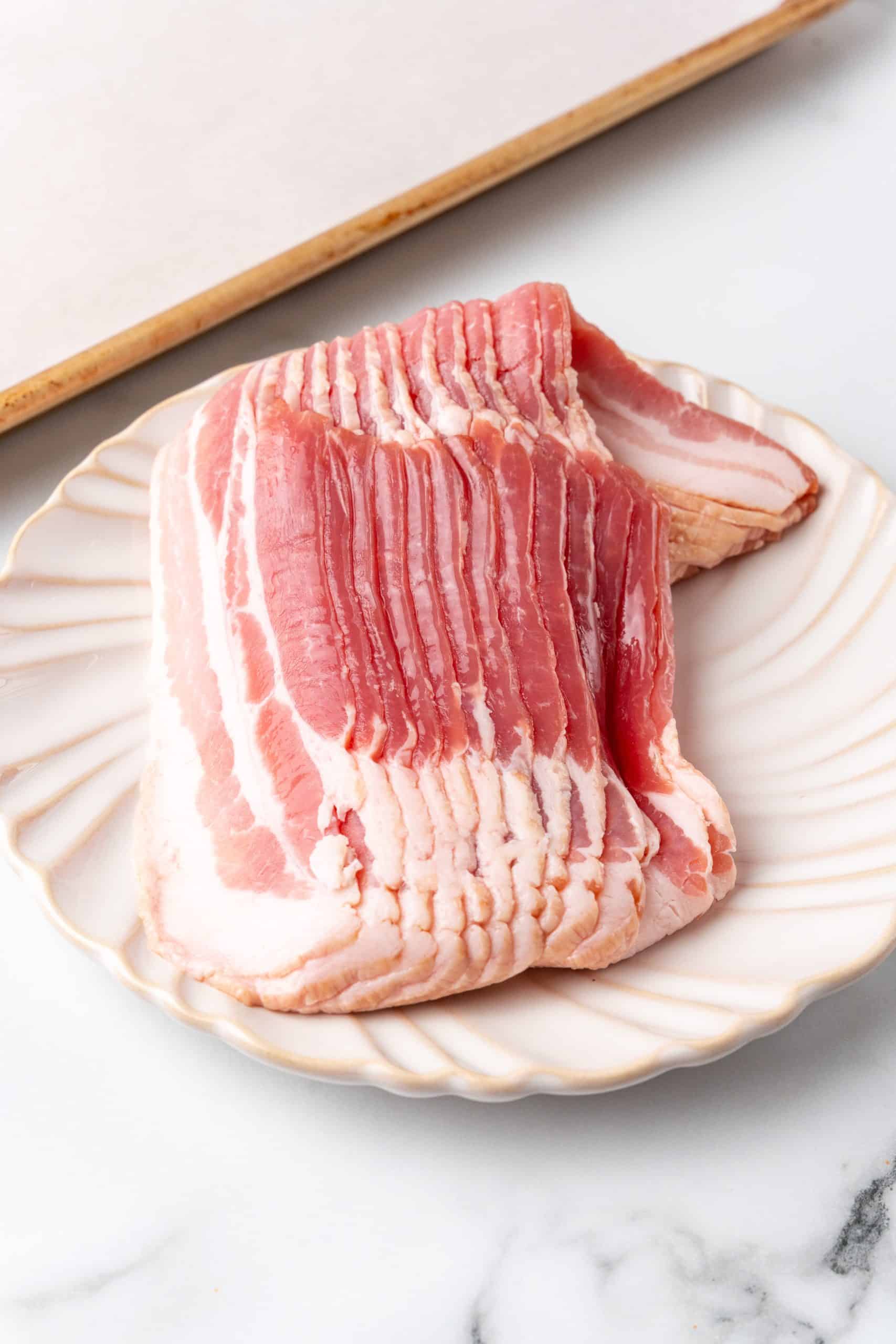 slices of uncooked bacon in a white plate