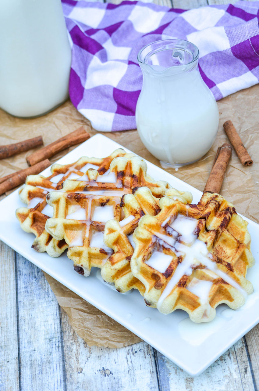 a row of cream cheese glazed cinnamon roll waffles on a white platter