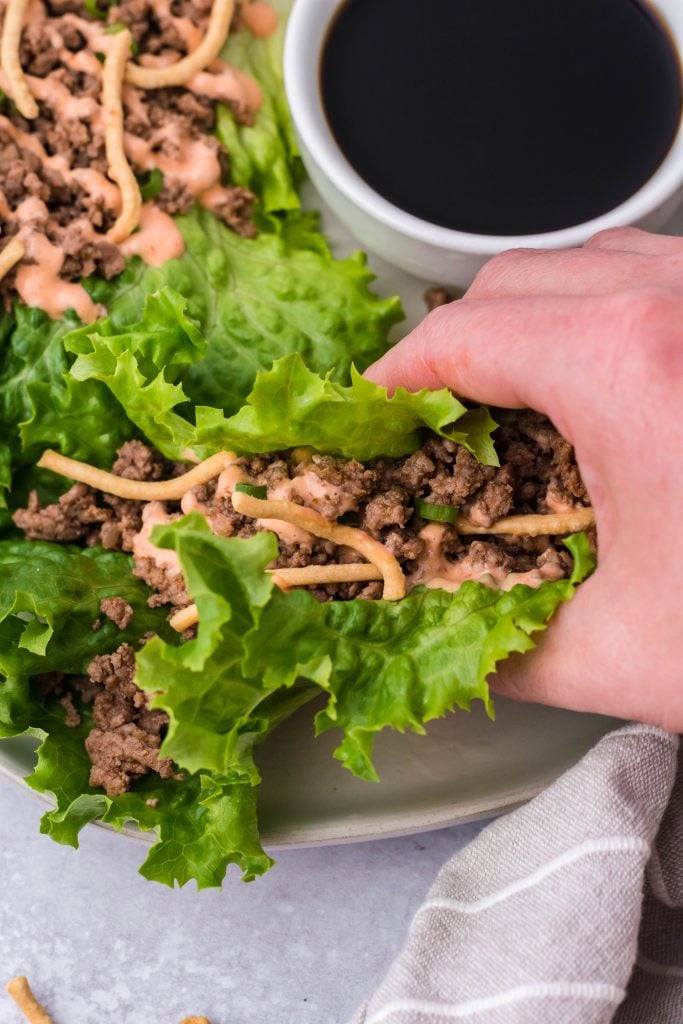 a hand holding up a beef stuffed lettuce wrap