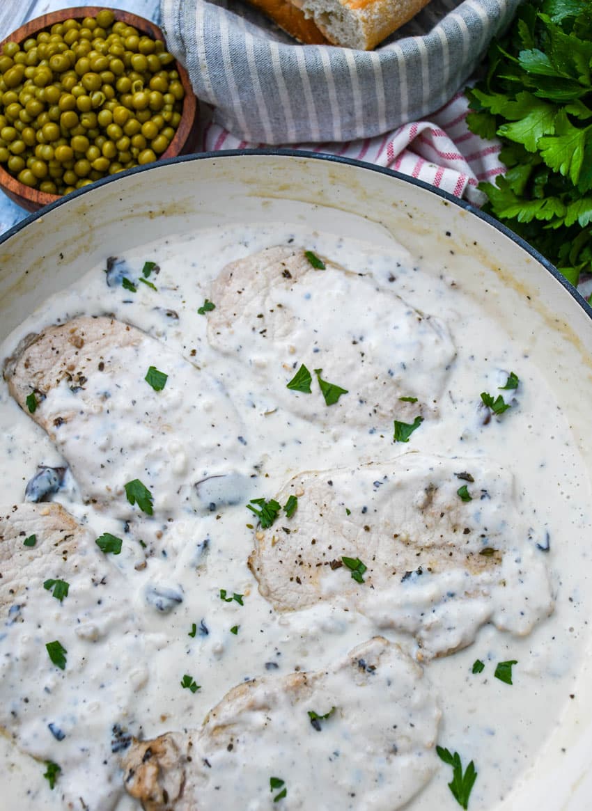 herbed pork chops in mushroom gravy in a large cast iron skillet