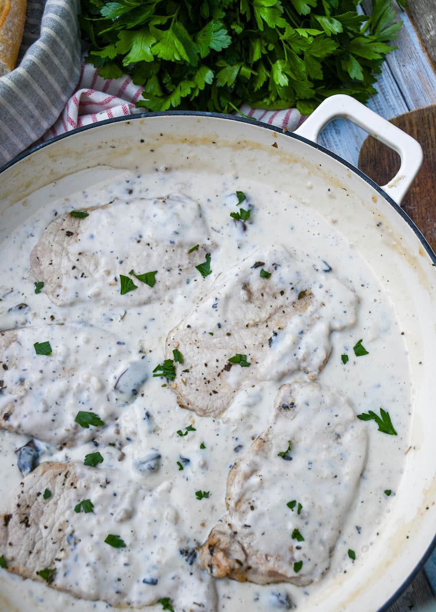 herbed pork chops in mushroom gravy in a large cast iron skillet