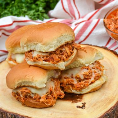 three crockpot chicken parmesan sliders stacked on a wooden cutting board