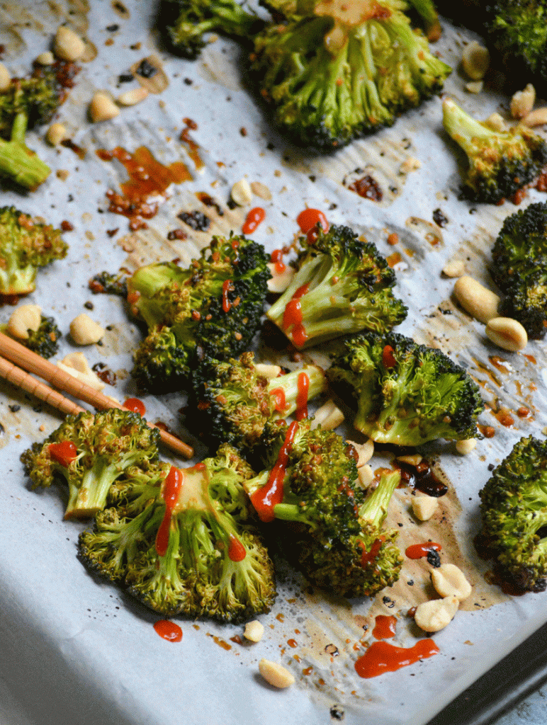 baked sriracha broccoli on white parchment paper with a pair of light brown chop stix
