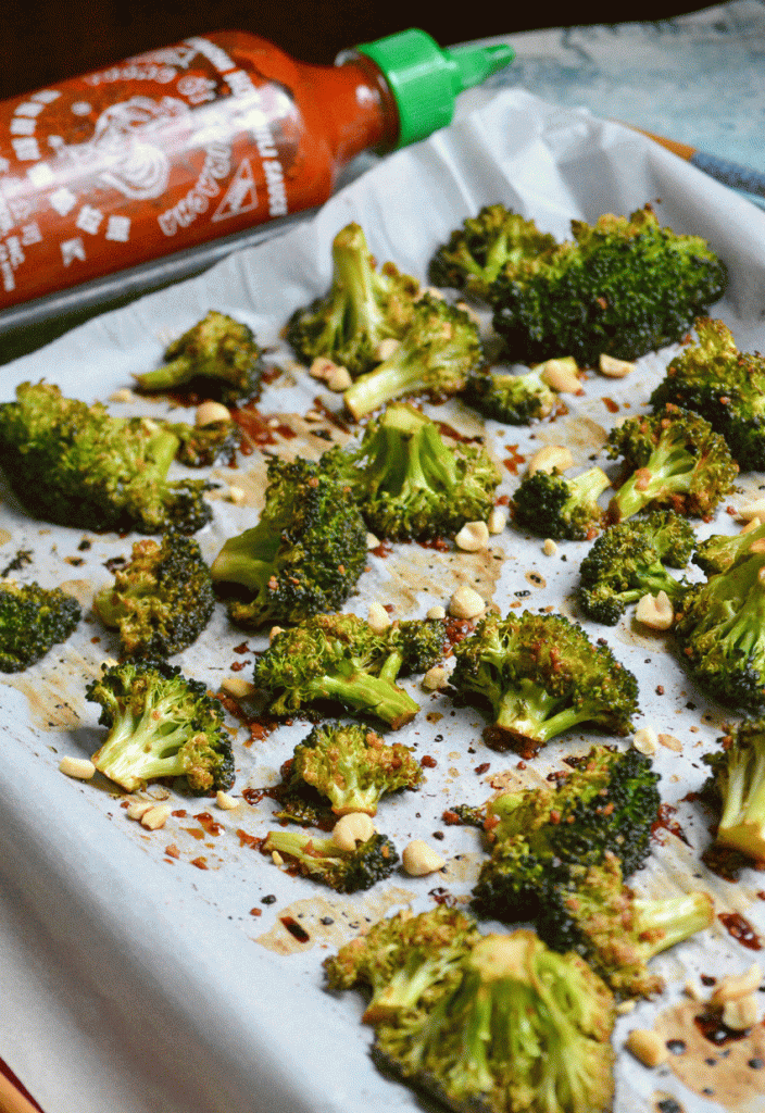 baked sriracha broccoli on a white parchment paper lined baking sheet