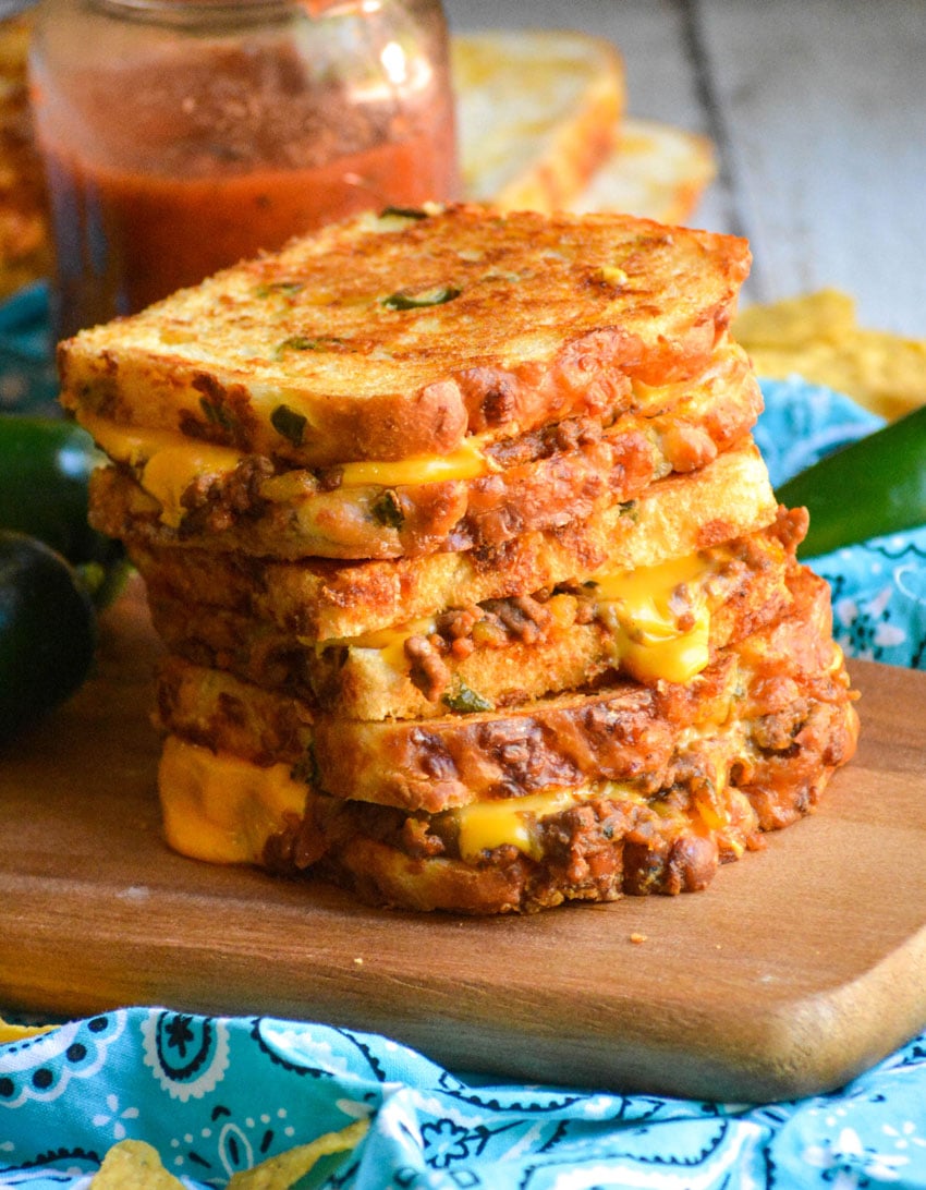 a stack of tex mex grilled cheese sandwiches on a wooden cutting board