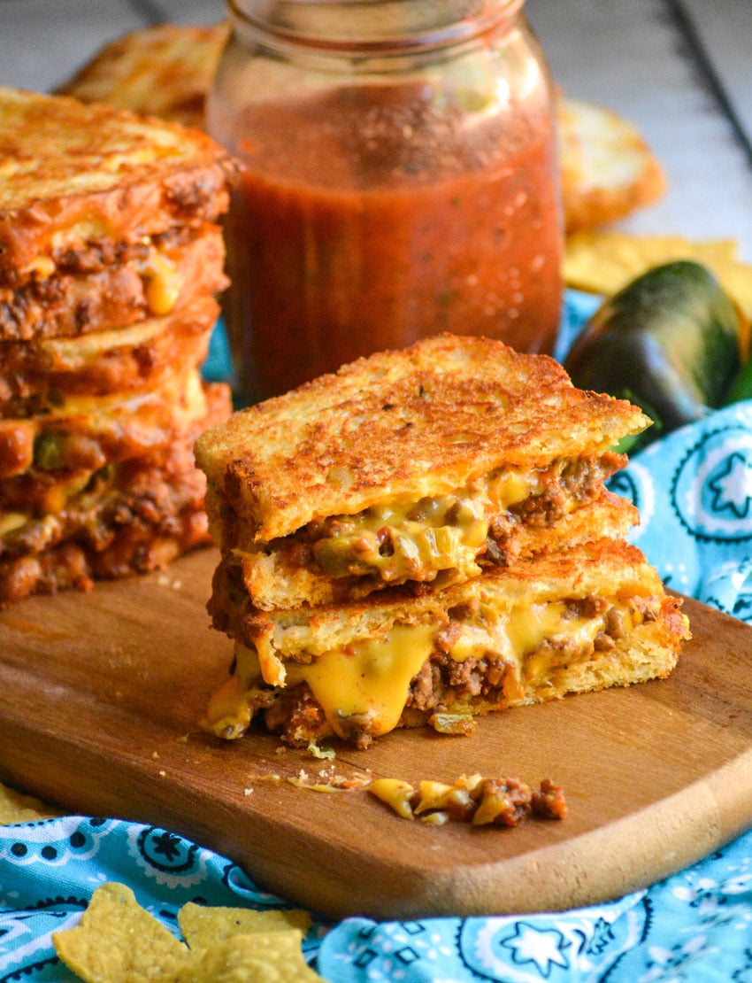 two halves of a cheesyTex Mex grilled cheese stacked together on a wooden cutting board