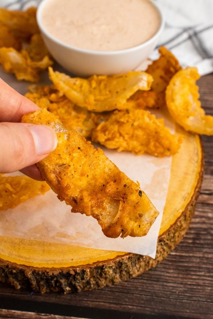 a hand holding up a fried bloomin onion bite